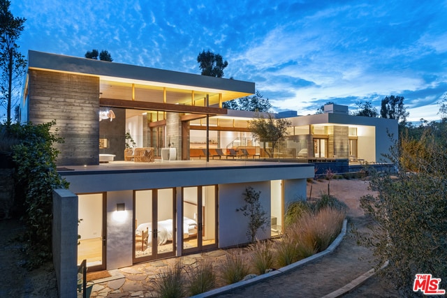 back house at dusk featuring a balcony