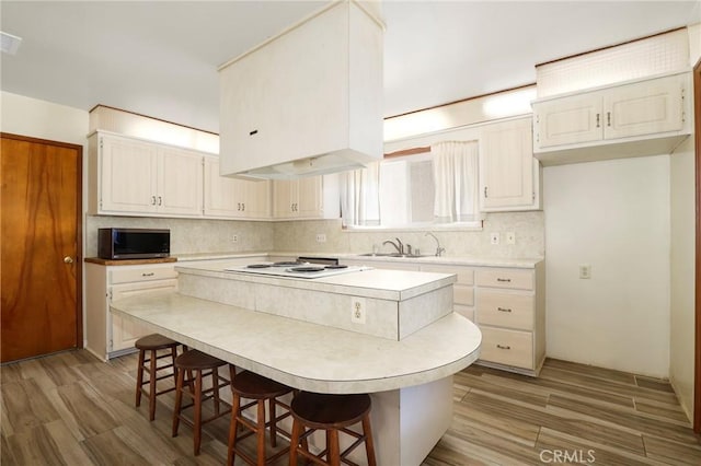 kitchen featuring a kitchen bar, white cabinets, light hardwood / wood-style flooring, and a kitchen island