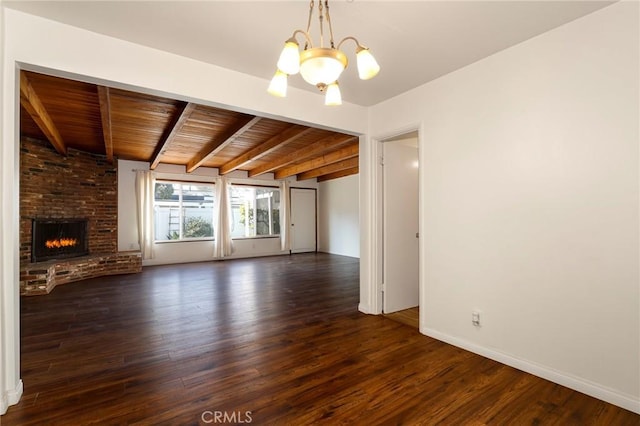 unfurnished living room featuring beam ceiling, a brick fireplace, wood ceiling, dark hardwood / wood-style floors, and a notable chandelier