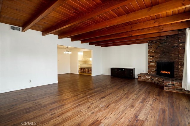 unfurnished living room featuring a notable chandelier, beamed ceiling, wooden ceiling, a fireplace, and dark hardwood / wood-style flooring