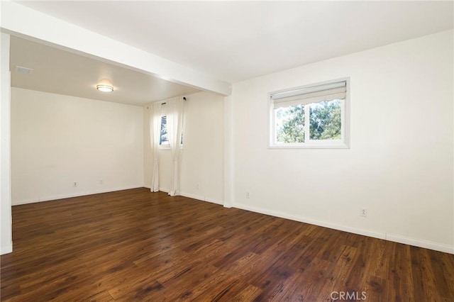 spare room featuring dark hardwood / wood-style flooring and beamed ceiling