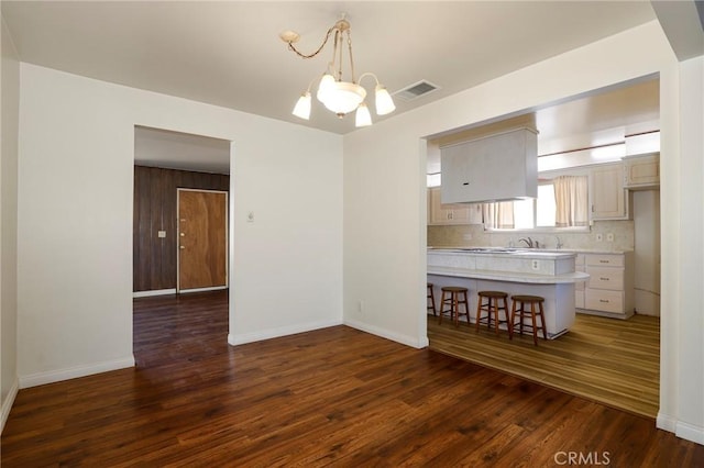 unfurnished dining area featuring sink, dark hardwood / wood-style flooring, and a notable chandelier