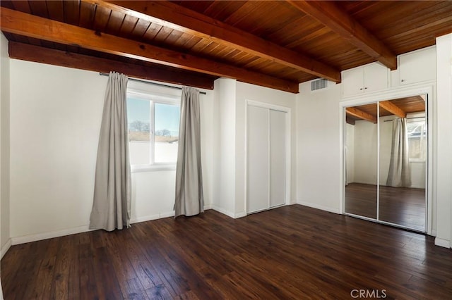 unfurnished bedroom featuring beam ceiling, dark wood-type flooring, and wooden ceiling