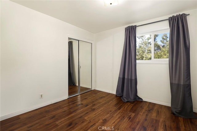 unfurnished bedroom featuring a closet and dark hardwood / wood-style flooring