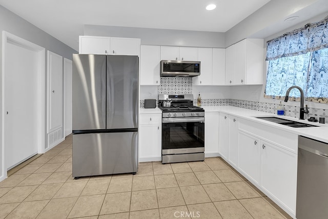 kitchen featuring sink, white cabinets, light tile patterned floors, decorative backsplash, and stainless steel appliances