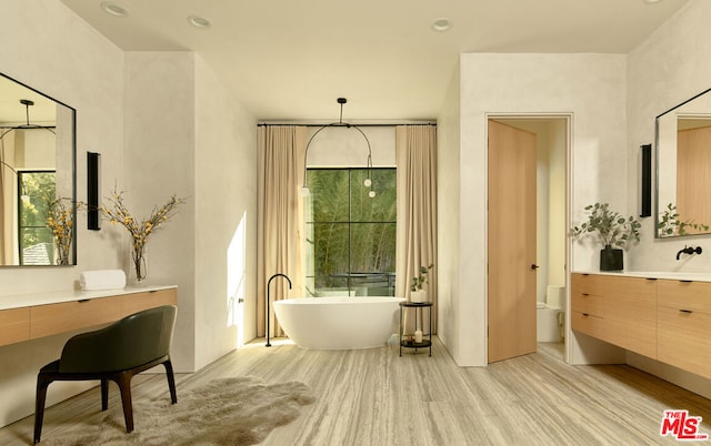 bathroom with a tub to relax in, hardwood / wood-style flooring, vanity, and toilet