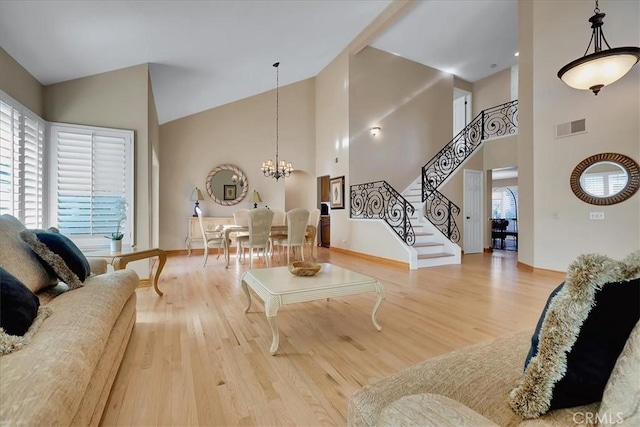 living room with wood-type flooring, a healthy amount of sunlight, a chandelier, and high vaulted ceiling