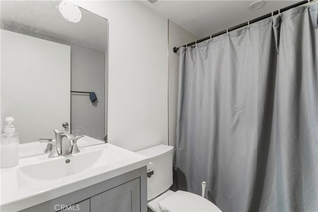 bathroom featuring toilet, vanity, and walk in shower