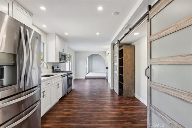 kitchen with sink, a barn door, white cabinetry, and stainless steel appliances