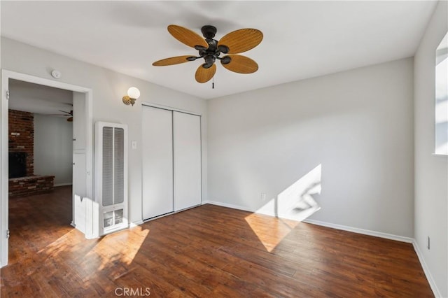 unfurnished bedroom with ceiling fan, dark hardwood / wood-style floors, a closet, and a fireplace