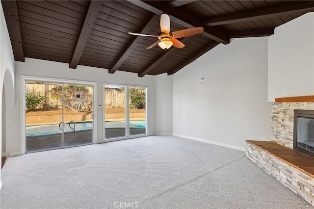 unfurnished living room with a stone fireplace, wooden ceiling, carpet, vaulted ceiling with beams, and ceiling fan