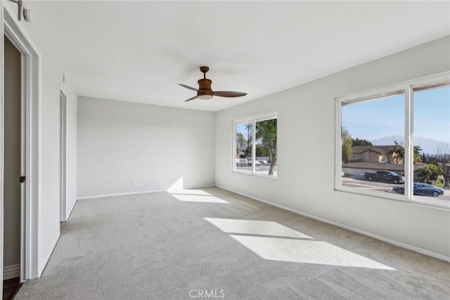 carpeted empty room featuring a mountain view and ceiling fan