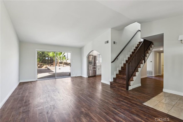 unfurnished living room featuring dark wood-type flooring and vaulted ceiling