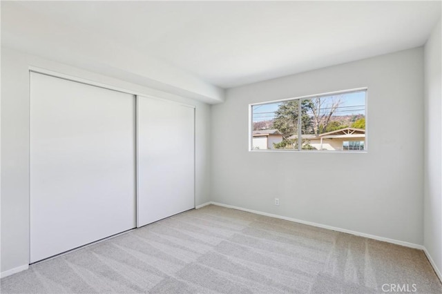 unfurnished bedroom featuring a closet and light colored carpet