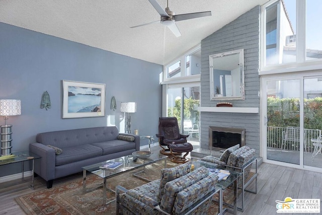 living room featuring a fireplace, a textured ceiling, hardwood / wood-style flooring, ceiling fan, and lofted ceiling