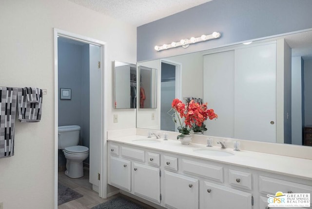 bathroom featuring vanity, toilet, hardwood / wood-style floors, and a textured ceiling