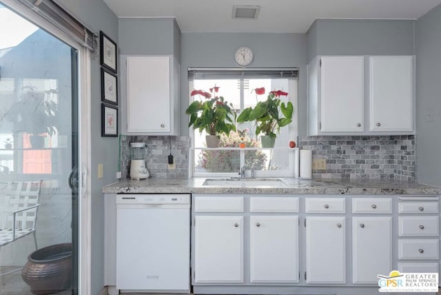 kitchen with light stone countertops, dishwasher, white cabinetry, sink, and backsplash