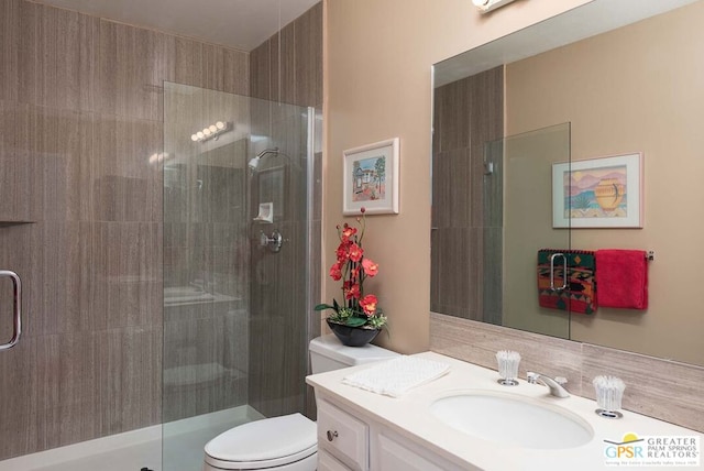 bathroom featuring toilet, a shower with shower door, and vanity