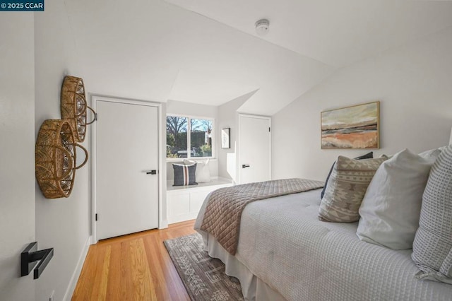 bedroom with lofted ceiling and light hardwood / wood-style floors