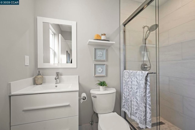 bathroom featuring vanity, a shower with shower door, and toilet