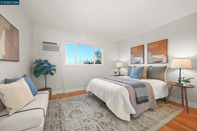 bedroom featuring hardwood / wood-style floors and a wall mounted air conditioner