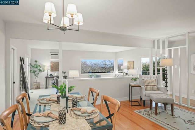 dining area with a wall mounted AC, a notable chandelier, and light wood-type flooring