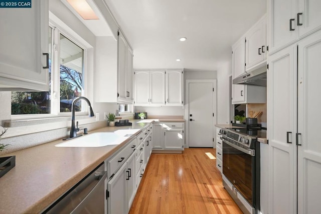 kitchen featuring white cabinetry, appliances with stainless steel finishes, light hardwood / wood-style floors, and sink