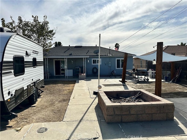 rear view of property featuring a patio area and a fire pit