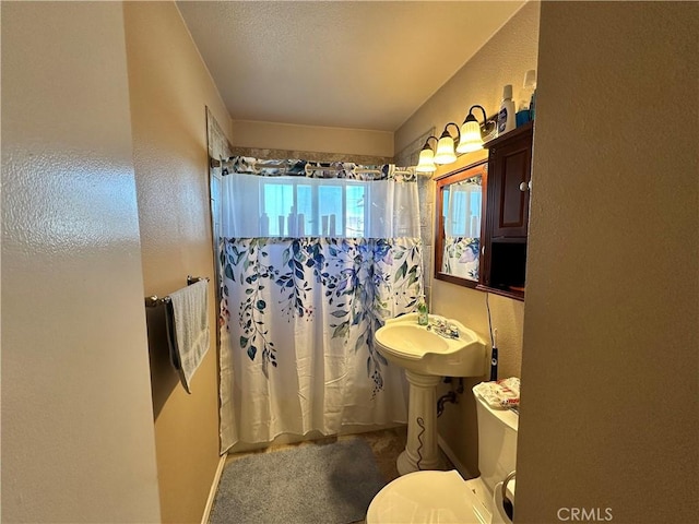 bathroom with a textured ceiling, toilet, and a shower with curtain