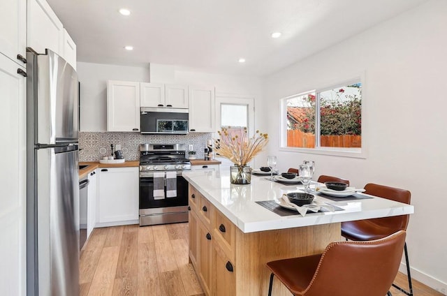 kitchen with tasteful backsplash, stainless steel appliances, a breakfast bar, and white cabinets