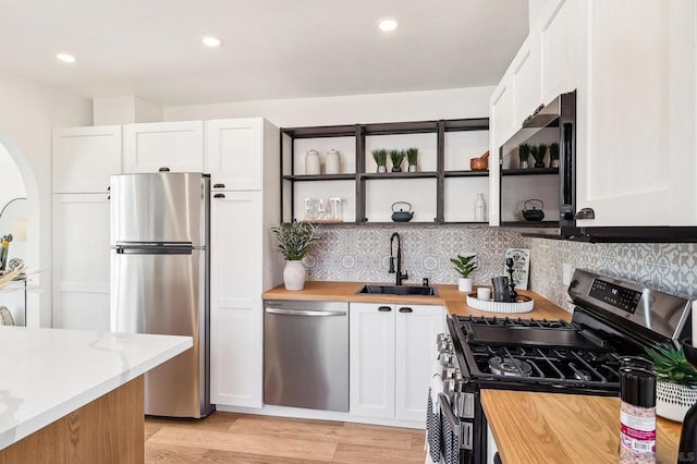 kitchen with butcher block counters, sink, appliances with stainless steel finishes, decorative backsplash, and white cabinets