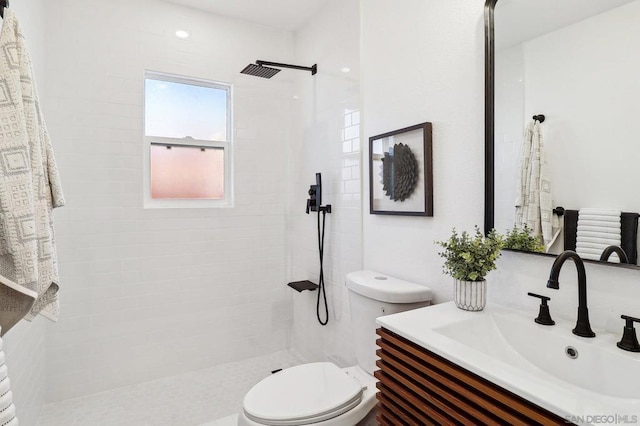 bathroom with tiled shower, vanity, and toilet