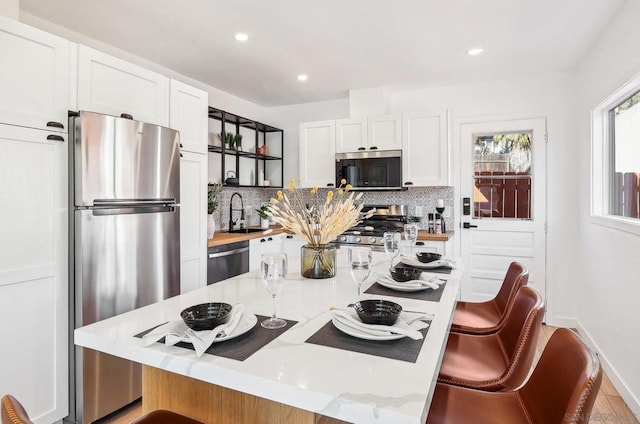 kitchen with tasteful backsplash, a breakfast bar area, stainless steel appliances, and white cabinets