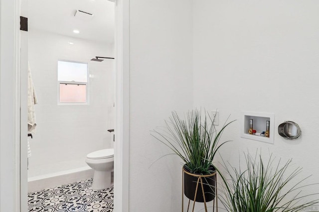 bathroom with tiled shower, tile patterned floors, and toilet