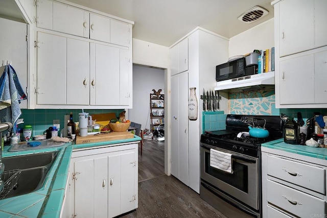 kitchen featuring dark wood-type flooring, white cabinetry, stainless steel gas stove, sink, and backsplash