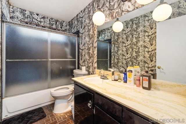 full bathroom featuring vanity, shower / bath combination with glass door, and toilet