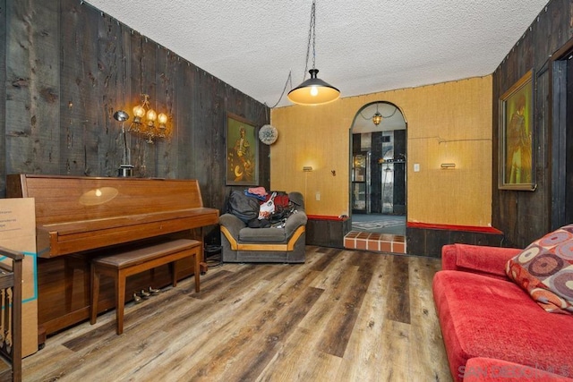 living area featuring wood walls, hardwood / wood-style floors, and a textured ceiling