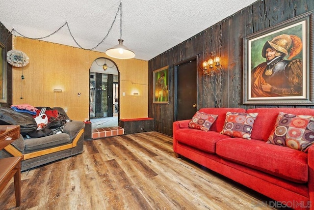 living room with a textured ceiling, hardwood / wood-style floors, and wooden walls