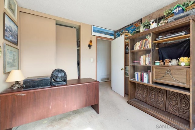 carpeted home office featuring a textured ceiling