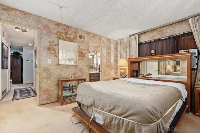 bedroom featuring light colored carpet, a textured ceiling, and ensuite bathroom