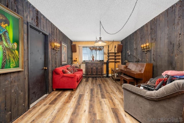 living area with wood walls, light hardwood / wood-style flooring, and a textured ceiling