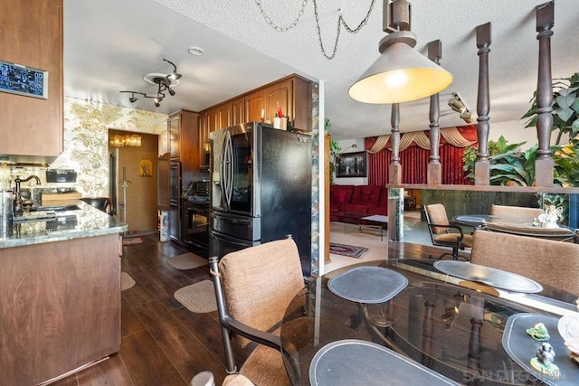 kitchen featuring a textured ceiling, dark hardwood / wood-style flooring, sink, stainless steel fridge, and light stone counters