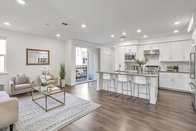 kitchen featuring stainless steel appliances, white cabinetry, a breakfast bar, and an island with sink