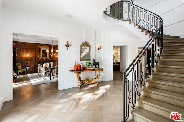 stairs featuring a chandelier and parquet floors