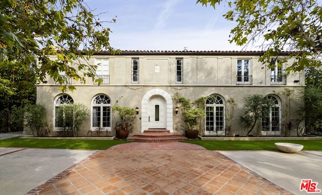 view of front of property featuring a patio, a balcony, and a front lawn