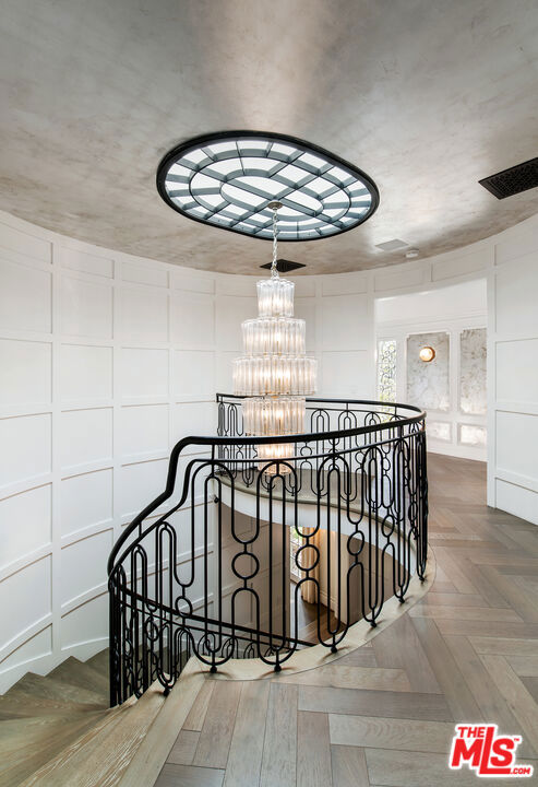 stairway with a chandelier and parquet floors