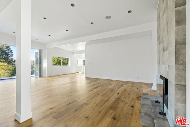 unfurnished living room with light hardwood / wood-style floors, lofted ceiling, and a fireplace