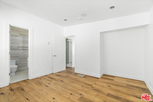 unfurnished bedroom featuring wood-type flooring and ensuite bath