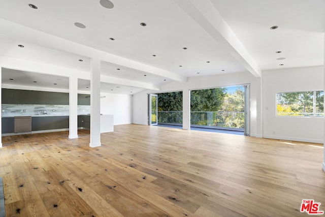 unfurnished living room with light hardwood / wood-style floors and vaulted ceiling with beams