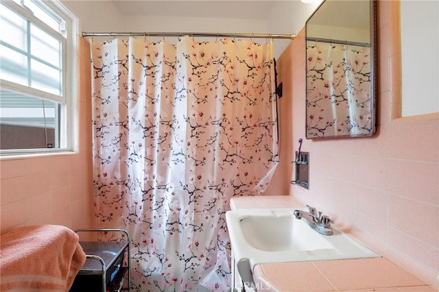 bathroom with sink, backsplash, tile walls, and curtained shower